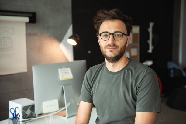 Casually dressed caucasian guy posing in office.